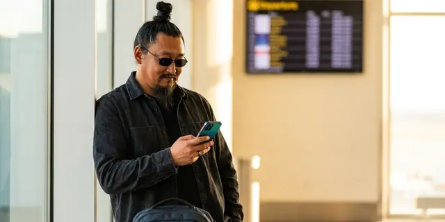 A traveller looking at his phone at an airport gate